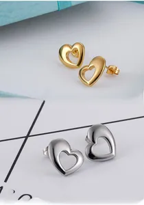Détails macro des boucles d'oreilles cœur évidé en finitions or et argent polies