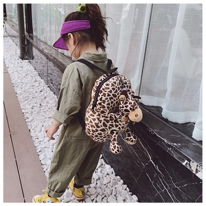 Cute giraffe cartoon backpack for kids with brown spots and plush doll on a girl outdoors