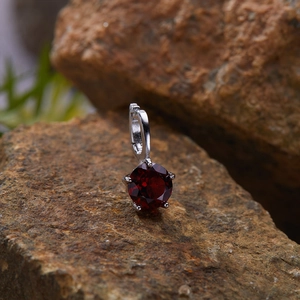 Macro shot of a red gemstone pendant set in S925 silver on a natural rock background