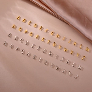 DIY A-Z initial charms in gold and silver finish on soft pink silk background