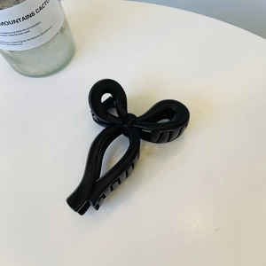 Detail shot of a matte black ribbon bow hair claw clip on a clean white surface