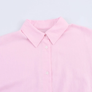 Detail view of pink linen shirt collar and white buttons with textured fabric close-up