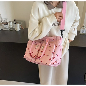 Detailed view of pink tote bag with cherry print and multiple functional zip pockets