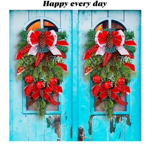 Detail of two Christmas door swags with red bells, ribbons and pinecones on blue wood