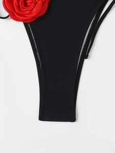 Detailed macro view of black bikini bottom with 3D red rose decoration and side ties