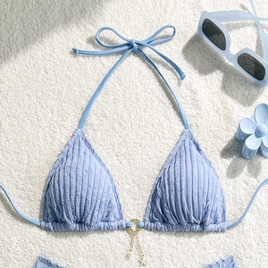 Detail of light blue textured bikini top with starfish and pearl charms on a gold ring