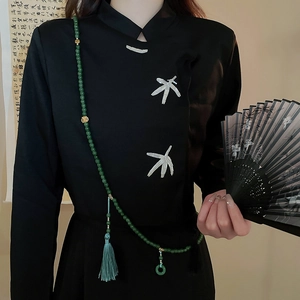 Detail of green beaded tassel pendant with jade charm on black embroidered cheongsam