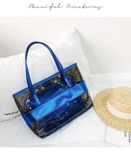 Blue transparent PVC jelly tote bag with metallic handles and inner pouch on white bedding