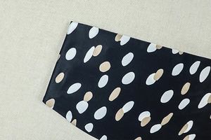 Detailed macro view of black satin fabric with irregular white polka dots texture