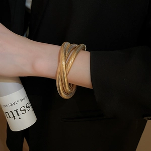 Detail of layered gold spiral cuff bracelet showing textured metal coils on model