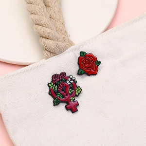 Detail of red rose and feminist symbol enamel pins pinned on a beige canvas bag