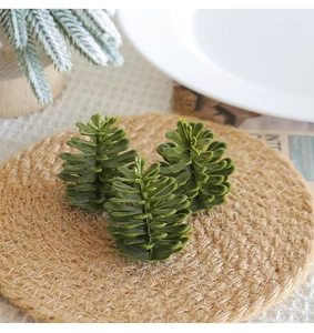 Three green plastic pine cones on a woven coaster for festive Christmas table decor