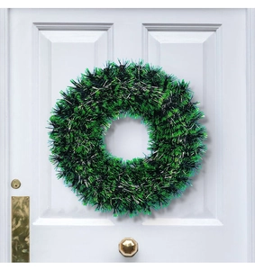 Festive green and black Christmas tinsel wreath displayed on a classic white door