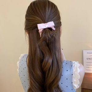 Close-up of a pink satin bow hair clip styled in a half-up long hair arrangement
