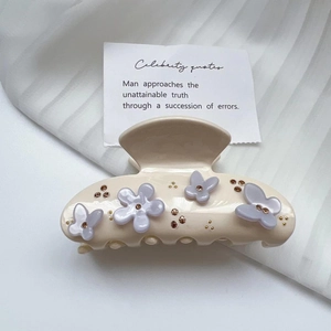Détail de la pince à cheveux en acétate crème avec fleurs lilas et papillons en cristal