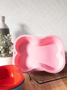 Close-up of pink bone-shaped silicone baking mold on a black metal wire rack