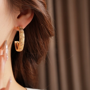 Close-up of golden C-shaped floral earrings with diamonds on female model side profile