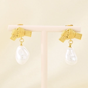 Close-up of French vintage bow-knot pearl earrings on a pink elegant jewelry stand