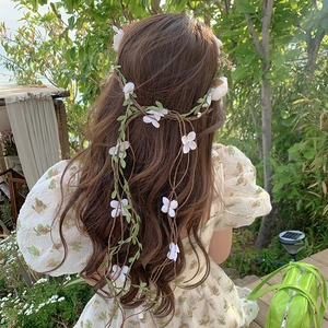 Fairy style white floral headband with green leaves on long wavy hair for photo shoot