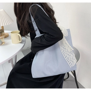 Detail of light blue polka dot tote bag with large white lace bow and canvas texture