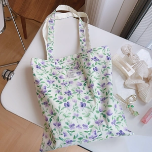 Dettaglio borsa tote in tela a fiori con motivi viola ed etichetta in tessuto