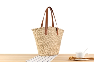 Detail view of a woven tote bag with brown leather handles on a striped fabric tabletop
