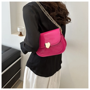 Detail of bright pink patent leather shoulder bag with golden heart clasp and chain strap