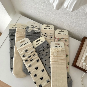 Dettaglio di calze dolci con fiocchi, pois e pizzo disposte su un piano bianco