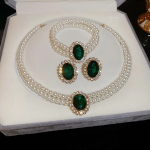 Close-up of double-layer pearl jewelry set with emerald green oval gemstones and gold plating