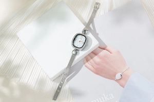 Close-up of elegant oval rhinestone watch with silver mesh band and marble dial
