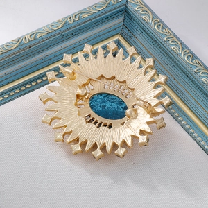 Detail shot of vintage sunburst brooch with gold metal plating and blue enamel center