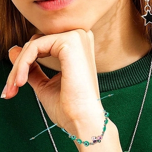 Handmade woven butterfly bracelet with green evil eye beads and gold metal accents