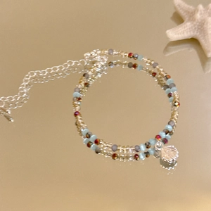 Detail eines Perlenarmbands mit Seestern- und Muschelanhängern für den Strandurlaub