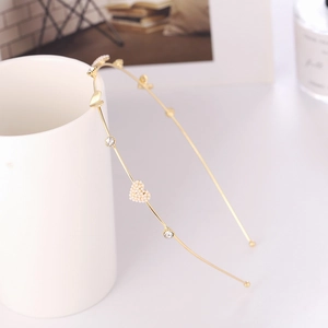 Elegant gold metal headband featuring heart-shaped pearls and crystals on a white cup