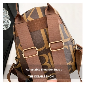 Detail of adjustable thick nylon shoulder straps with gold hardware on a brown lettered backpack