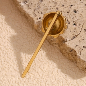 Macro shot of 18K gold plated crown hair clip on natural stone background