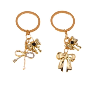 Elegant gold alloy keychain with pearl and rhinestone bowknot pendants on white background