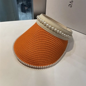 Detail of bright orange woven sun hat with white pearl beads on beige headband