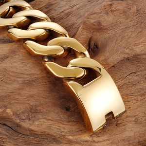 Close-up of high-polished gold Cuban chain bracelet on natural wood background texture