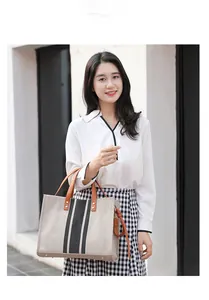 Detailed view of canvas tote bag with leather handles and vertical stripe accents