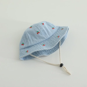 Detail of blue denim bucket hat featuring embroidered cherry patterns and adjustable strap