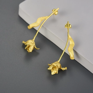 Detail of matte gold tulip drop earrings on minimalist white display stand