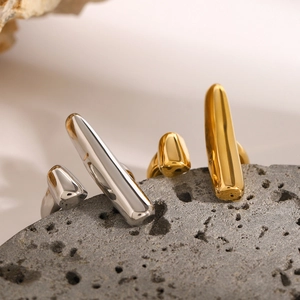 Minimalist geometric stainless steel rings in gold and silver finish on volcanic stone