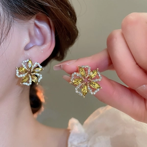 Close-up of elegant flower stud earrings with yellow crystals and sparkling white stones