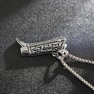 Detail shot of a star-patterned cowboy boot pendant on a steel chain for men