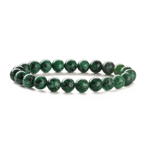 Macro detail of natural green gemstone bead bracelet with unique black mineral spots