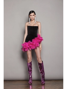 Detail of black strapless mini dress with vibrant pink feathers and purple metallic boots