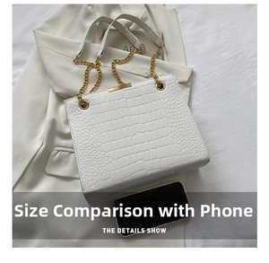 Close-up of white crocodile embossed tote bag with gold chain and phone size comparison