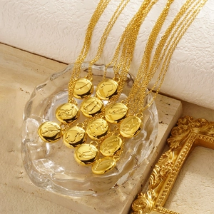 Gold zodiac coin pendant necklaces in stainless steel displayed on a glass tray
