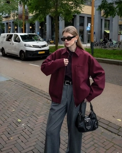 Street style view of wine red zip-up cargo jacket paired with grey striped wide-leg pants